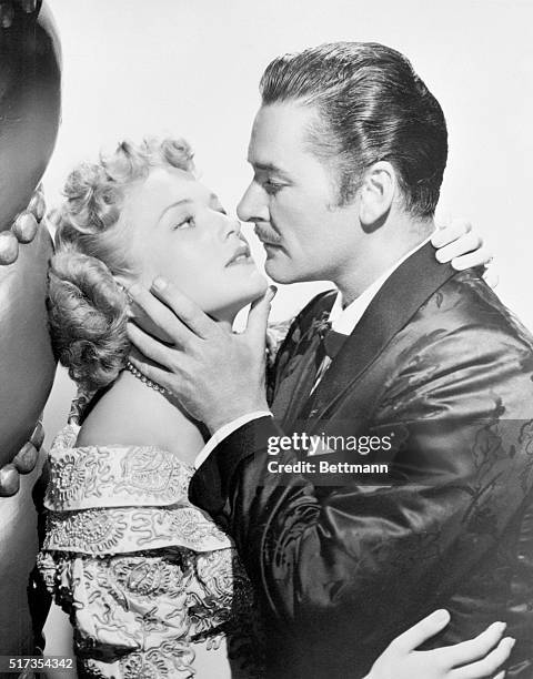 From Reel to Real. Hollywood: Errol Flynn, swashbuckling hero of the motion picture screen, engages in a passionate love scene with Patricia Wymore...