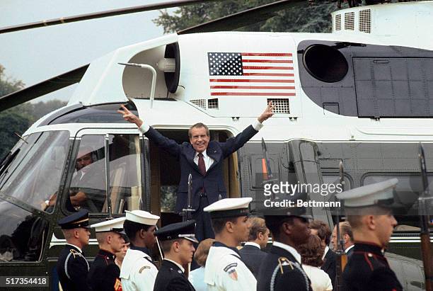 As he boards the White House helicopter after resigning the presidency, Richard M Nixon smiles and gives the victory sign.