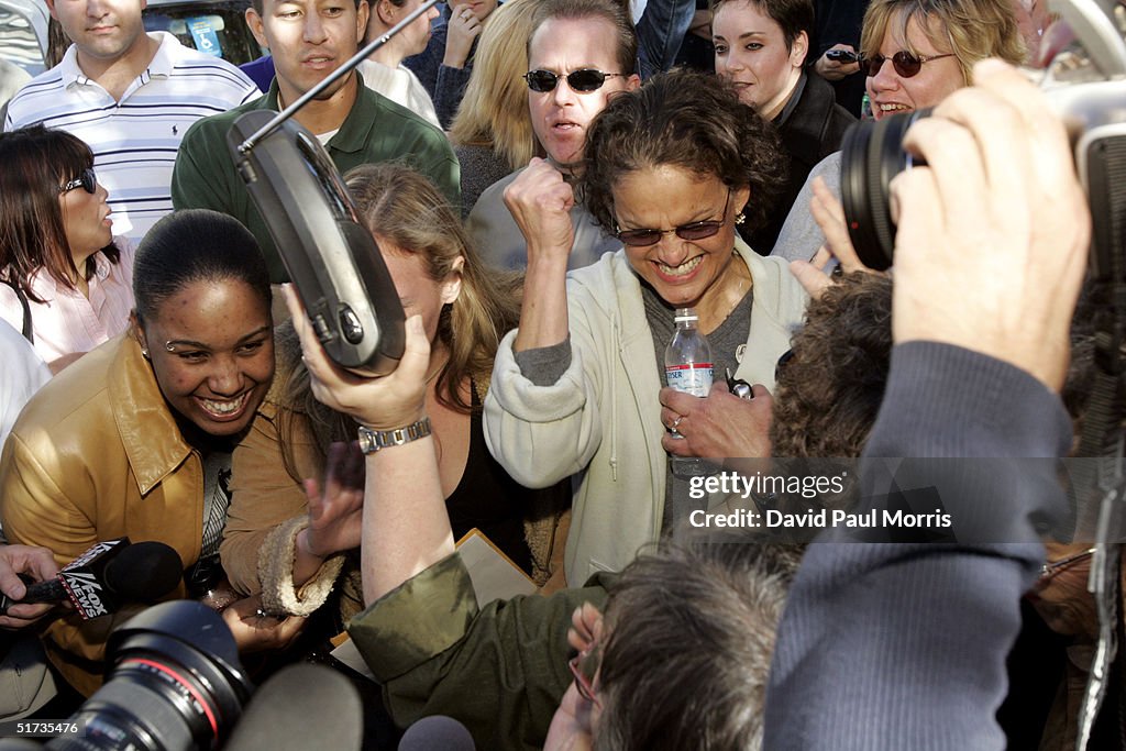 A group of people listening to a radio outside the Redwood City... News