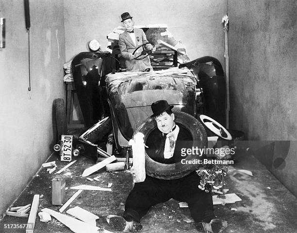 Stan Laurel and Oliver Hardy crashing through the wall in their automobile. Still from a 1938 movie.