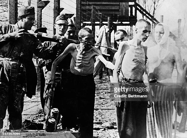 World War II concentration camps: Two former inmates of Mittelgladblach Camp being sprayed by allied soldiers against communicable diseases. Undated...