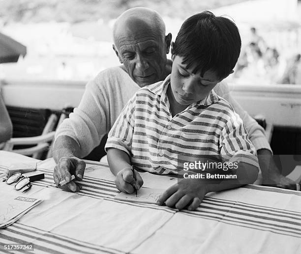 La Garoupe, France: Famed Spanish painter and sculptor Pablo Picasso takes sometime give his young son Claude some instruction in the rudiments of...