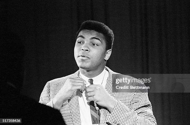 New York, NY- Heavyweight champion Cassius Clay adjusts his tie as he appears on a CBS-TV news program. Clay kept his title--for the time being,...