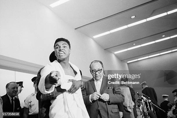 Challenger Muhammad Ali, when he was known as Cassuis Clay, strains to break away from a friend who held him as he tried to lunge at champion Sonny...