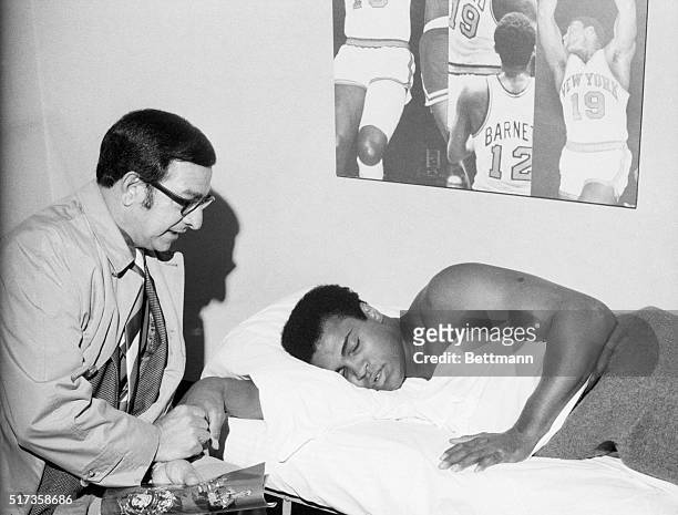 New York, NY- Manager Angelo Dundee sits by Muhammad Ali as he takes a nap a few hours after weigh-in at Madison Square Garden here, March 8. Ali...