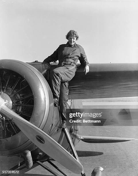 Amelia Earhart climbs aboard a small single-engine airplane.