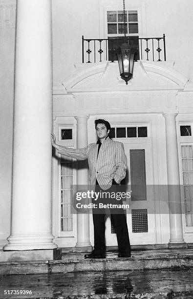 Memphis, TN-A thoughtful Elvis Presley leans against a massive pillar on the front porch of his traditional southern-style home, "Graceland," at...