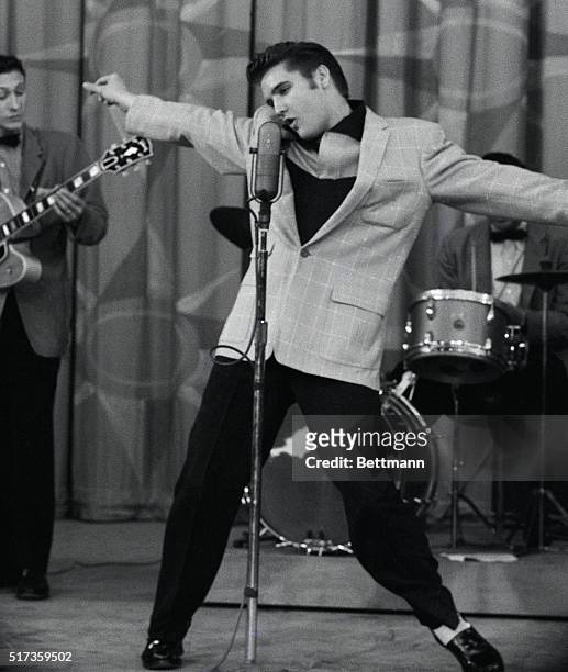 Hollywood, CA-His arms stretched out and his head swaying rhythmically from side to side, Elvis Presley loses himself as he pours out his song of woe.