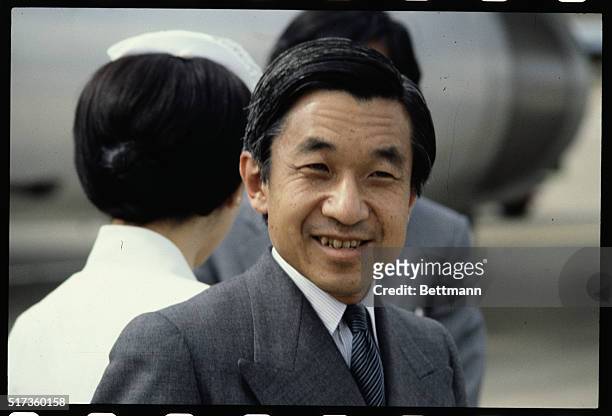 Close-up of Akihito, the Crown Prince of Japan, standing alone outside and smiling.