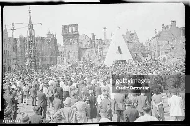 New housing one of their aims...War ruins provide a grim background during mass meeting of Social Democrats in Nurenberg Market. The huge "A" is the...