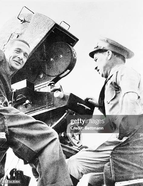 Charlie Chaplin wears his dictator costume behind the camera as he directs the 1940 film The Great Dictator. His cameraman Roland Totheroh is with...