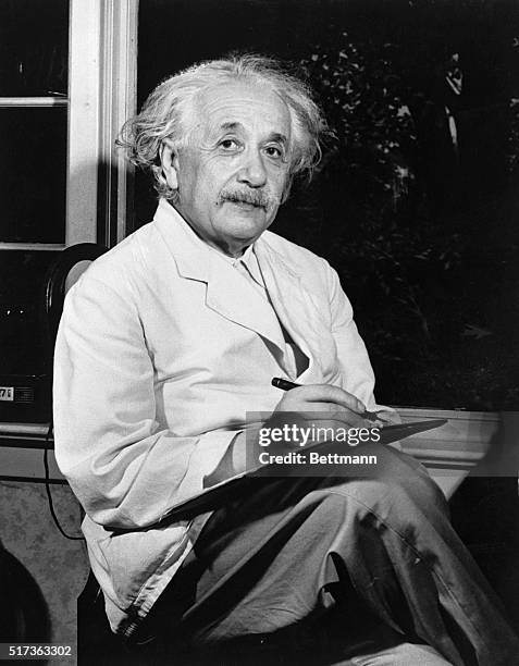 Dr. Albert Einstein is shown seated inside by the window, writing.