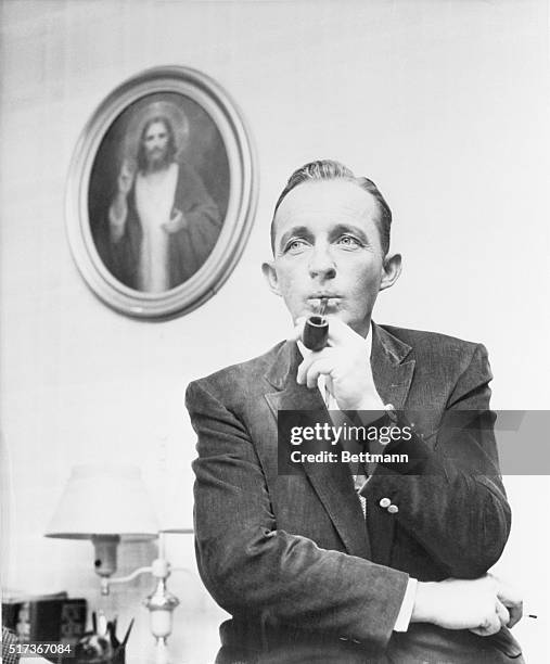 Singer Bing Crosby puffs reflectively on his pipe in his Hollywood home during an informal appearance on the CBS-TV program, Person to Person. The...