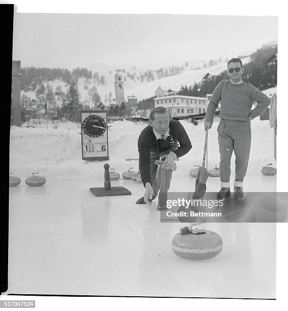 Noted British jockey Sir Gordon Richards watches the form of his turf colleague, Douglas Smith during a game of curling at the ice rink of the...