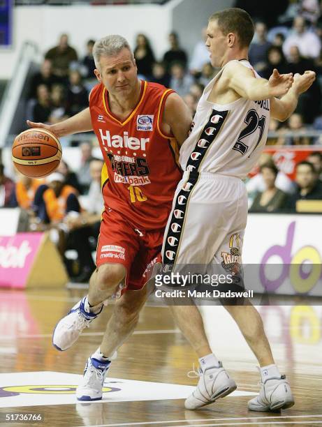 Andrew Gaze for the Tigers drives past Nathan Croswell for the Taipans during the NBL round 7 game between the Melbourne Tigers and the Cairns...