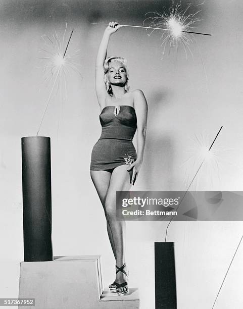 The full impact of this setting becomes apparent as Marilyn the screen star stands triumphant amid flashing sparklers. Even that spangle on the hem...