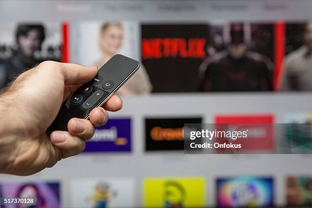 human hand holding the new apple tv siri remote - netflix stockfoto's en -beelden