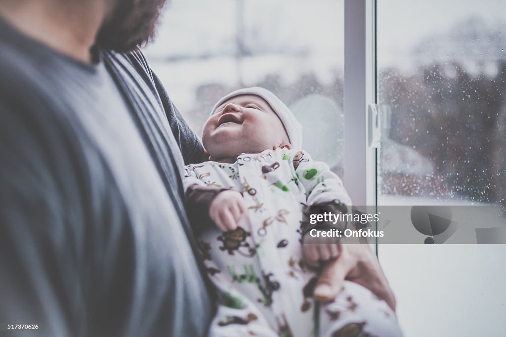 Liebenden Vater mit Neugeborenen Baby in der Nähe der Fenster im Winter