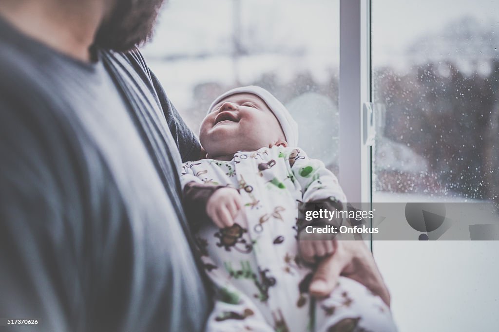 Loving Dad With Newborn Baby Close to Window in Winter