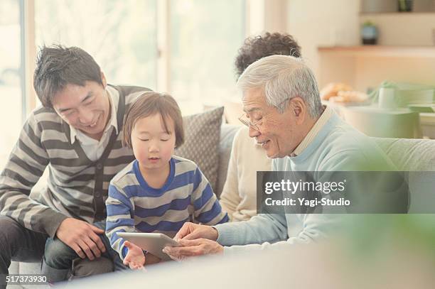 familie digitaltablett sich wie zu hause fühlen. - asian smiling father son stock-fotos und bilder