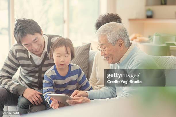 family using digital tablet together at home - grandmas living room 個照片及圖片檔