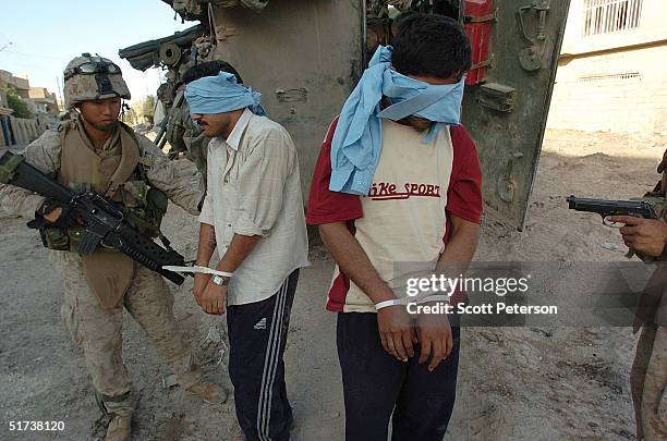 Marines of the 1st Light Armored Reconnaissance company handle two detainees during their search for insurgents November 13, 2004 in Fallujah, Iraq....