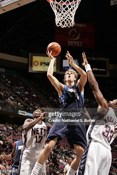 Dirk Nowitzki of the Dallas Mavericks attempts a layup against Alonzo Mourning and Eric Williams of the New Jersey Nets on November 13, 2004 Nets at...