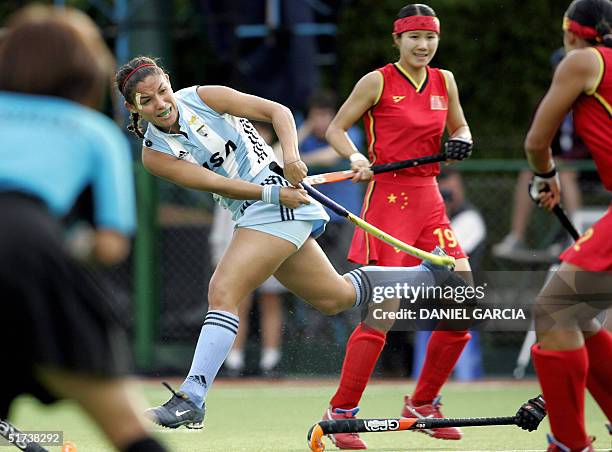 Argentine Soledad Garcia hits the ball between Chinese Chen Quiqi and Huang Xuejiao and umpire Kazuko Yasueda during the field hockey match for the...