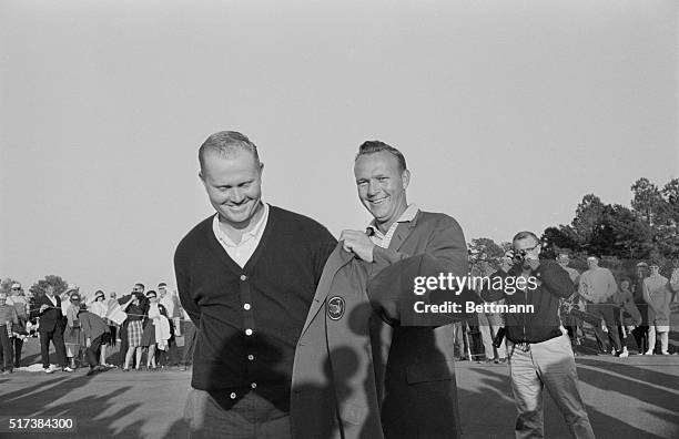 Fellow golf champion Arnold Palmer presents Jack Nicklaus with his green jacket after winning the 1963 Masters Tournament.