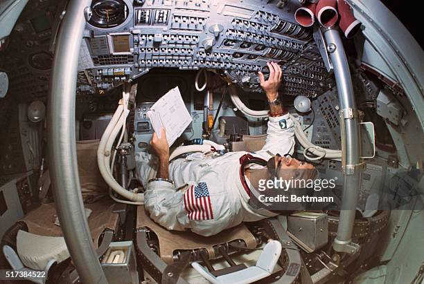 Michael Collins, Apollo 11 command module pilot, checks on technical material while in the Apollo Mission Simulator, which inside is an exact model...
