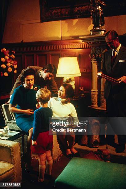 Prince Charles is shown here at home with his family for a quiet weekend at Sandringham. Prince Charles is looking over the shoulder of his mother...