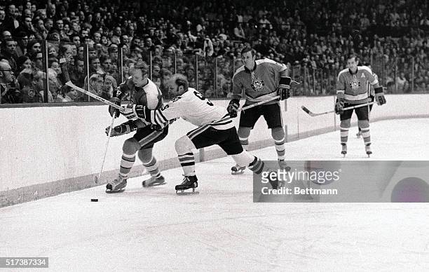 After some hard checking, Bobby Hull , of the Hawks, passes off to teammate Doug Mohns as Penguins' Ron Schock looks on in first period action 2/7.