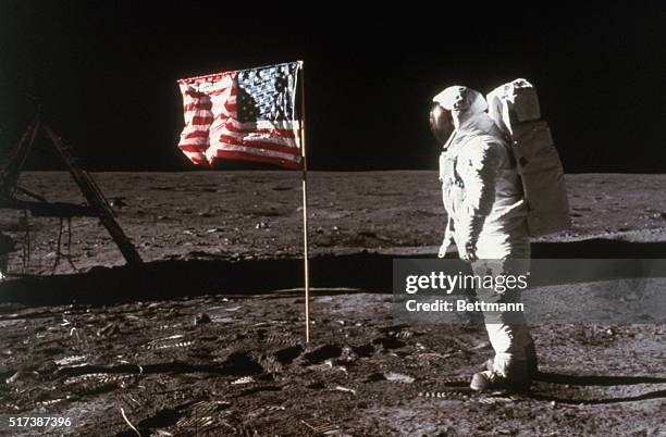 Astronaut Buzz Aldrin, lunar module pilot, stands beside an American flag placed on the moon during Apollo 11 extravehicular activity. He is...