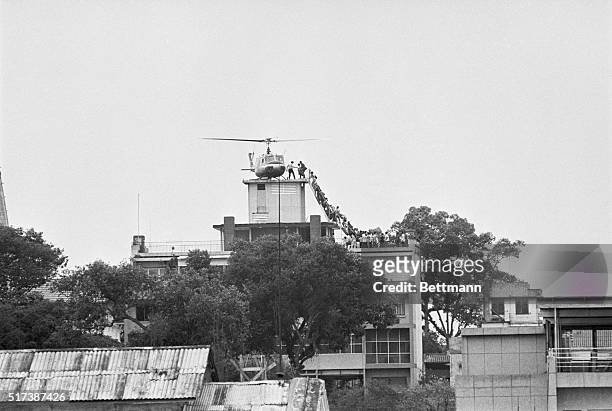 Employee helps Vietnamese evacuees onto an Air America helicopter from the top of 22 Gia Long Street, a half mile from the U.S. Embassy.