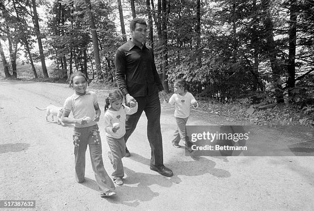 World heavyweight champ Muhammad Ali holds the hands of his twin daughters Jamalliah and Rahshoda as his daughter Miriam runs alongside at his...