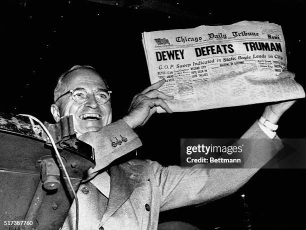 President Harry S. Truman gleefully displays a premature early edition of the Chicago Daily Tribune from his train in St. Louis, Missouri, after his...