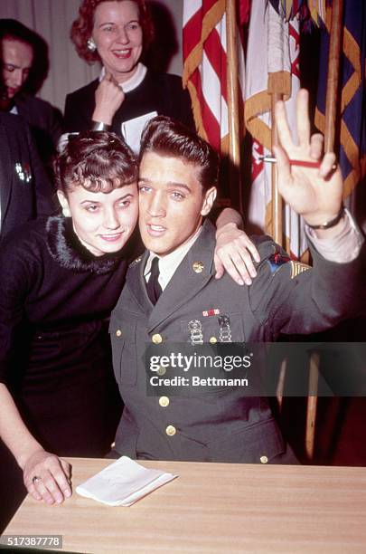 Elvis Presley prepares to signs an autograph and receives a hug from a fan after his return to the United States. Elvis completed an 18 month tour of...