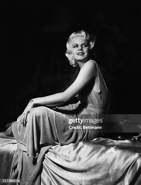 Full length portrait of Jean Harlow seated wearing velvet dress. Undated photograph.