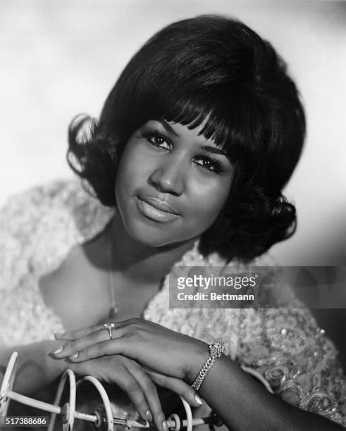 Seated portrait of R&B singer Aretha Franklin during her youth. In this photo her left hand is featured prominently with a diamond bracelet on her...