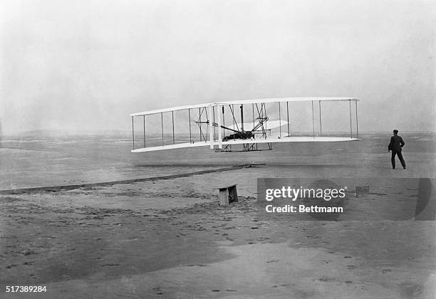 The Flyer takes off from Kill Devil Hill, with Orville Wright at the controls, while his brother Wilbur looks on, on December 17, 1903.