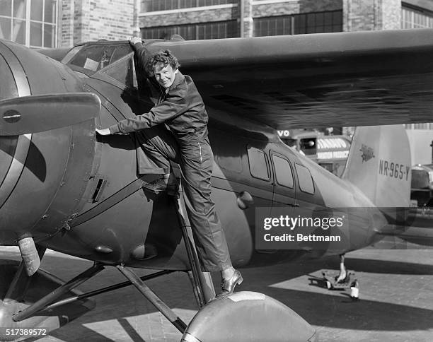 Amelia Earhart, , first woman to cross the Atlantic Ocean in an airplane. She is shown climbing into the cockpit. Undated photograph.