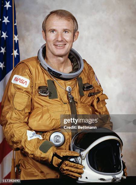 Johnson Space Center, Houston, Texas: Formal NASA portrait of Astronaut Vance D. Brand, seated before an American Flag and wearing a space suit with...