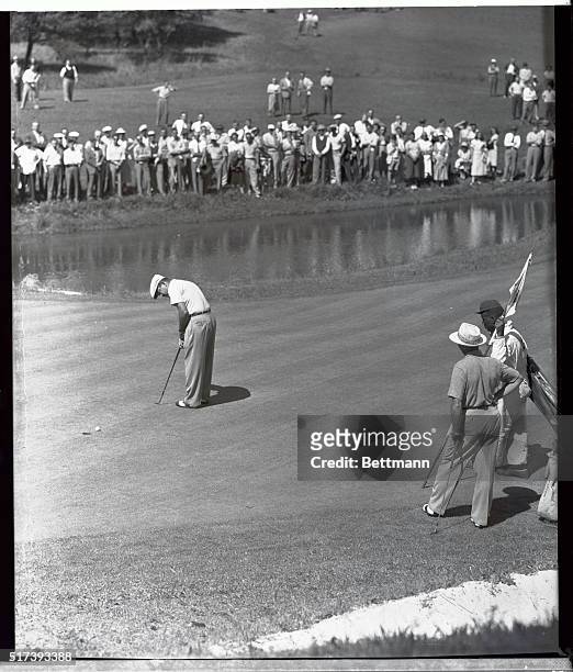 Johnny Palmer sinks a putt on the 12th hole during the third round of the Masters golf tournament, while his playing partner Sammy Snead watches....