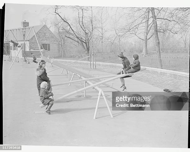 Children ride on a seesaw in the playground.