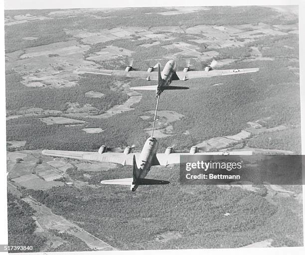 Fuel from the tanker is transferred under pressure to the B-29 medium bomber by means of the telescoping pipe extending from the tankers's tail.