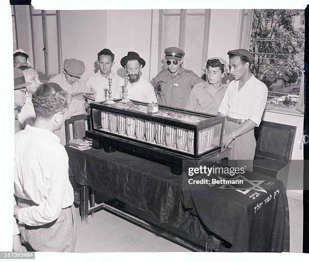 In the Tel-Aviv Rabbinate, residents of the city pray over a case containing the ashes of comrades cremated in Germany during the war. The large wood...