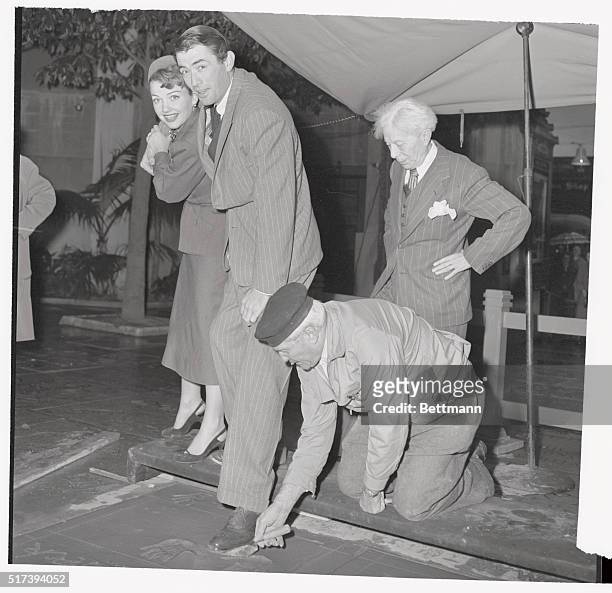 Footprints of fame are in the making here as actor Gregory Peck and actress Ann Baxter take turns placing their feet in wet cement in the forecourt...