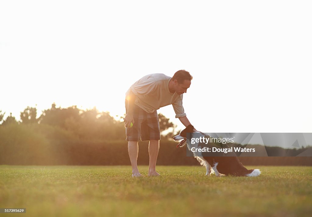 Dog and owner together in field.