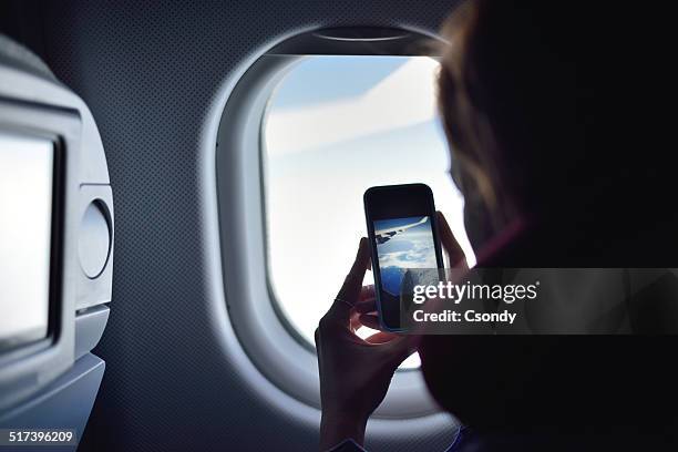 young woman taking a picture on an airplane - mobile on plane stock pictures, royalty-free photos & images