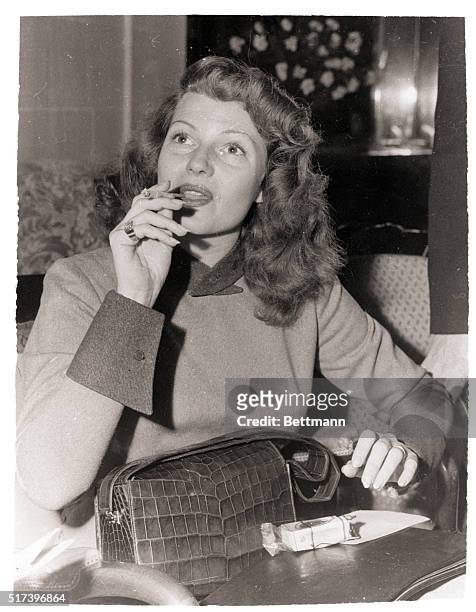 Madrid, Spain- Former motion picture star, Rita Hayworth, puffs on a cigarette while speaking to newsmen at her hotel in Madrid. She arrived in the...